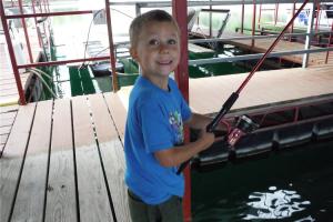 Young boy fishing from a boat dock