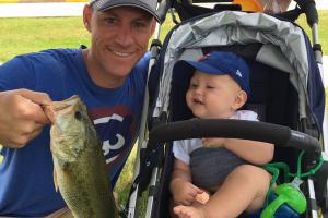 Young toddler in stroller with fahter hold a bass