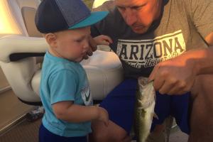 Young toddler looking at the bass his father is holding