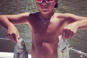 Two stripe bass held by a young angler