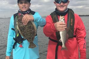 Two young men holding up the saltwater fish they caught