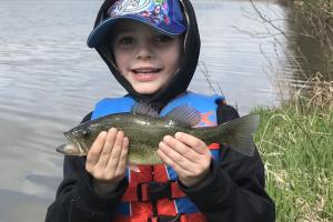 Young boy hold up his first fish