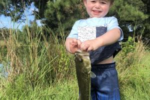 Young boy holding a bass by its mouth