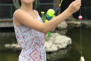 Young girl hold up a fish she caught at Bass Pros gone fishing event