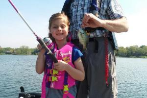 Girl angler standing with another angler holding bluegill