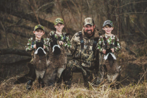 Rob Keck with his three grandsons each holding a goose