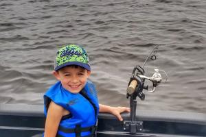Young boy maning a trolling rig on a boat