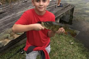 Boy on shore holding the bass fish he caught