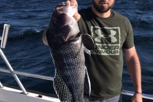 Saltwater angler on the sea hold a sea bass