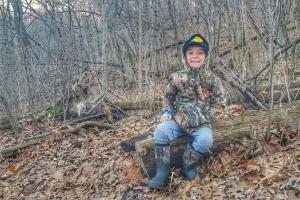 Young boy in a forest wearing camo