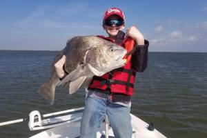Boy Saltwater angler holding a good size grouper