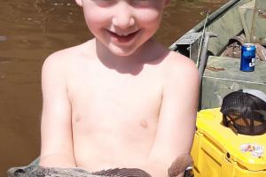 Young boy holding his 1st fish caught on his own