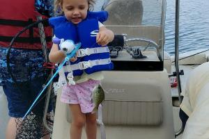 Young girl on a boat holding fishing blue rod and reel