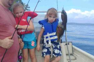 Two young girl anglers looking at two bluegill fish