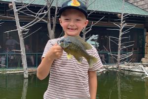 Young boy angler holding a fish in front of Bass Pro Shops