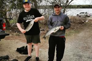 Two teen anglers holding stripe bass