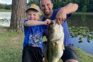 Father helping son holding 6.88 lb bass