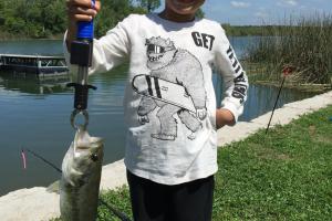 Young boy holding bass with weight scale