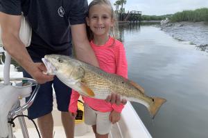 Young girl standing on boat posing with red drum