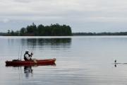Angler on a lake reeling in a fish from his kayak