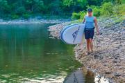 women_carrying_ascend_paddleboard_walking_along_shore